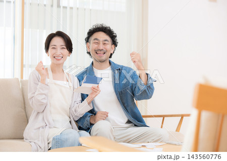 通帳を持つnisaや投資を多角化で貯蓄を増やしバランスで成功しガッツポーズ夫婦イメージカメラ目線笑顔 143560776