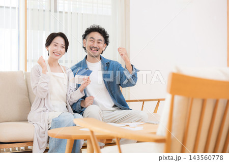 nisaや投資を多角化で貯蓄を増やしバランスで成功しガッツポーズ夫婦イメージカメラ目線笑顔 143560778