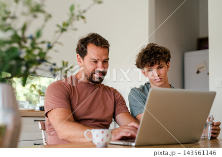 Father supporting teenage son checking university admission decision online. Father supporting teenage son checking university admission decision online. 143561146