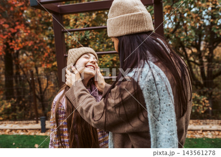 Portrait of beautiful mother with young daughter in the middle of autumn garden. 143561278