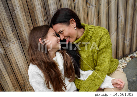 Portrait of beautiful mother with young daughter, sitting together and embracing. 143561302