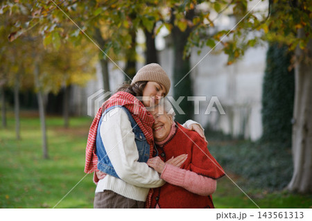 Portrait of a granddaughter on an autumn walk in the park with her grandmother. Portrait of a granddaughter on an autumn walk in the park with her grandmother. 143561313