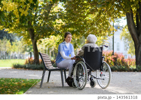 Sad elderly woman in wheelchair holding hands with her nurse, talking about her problems. Sad elderly woman in wheelchair holding hands with her nurse, talking about her problems. 143561318