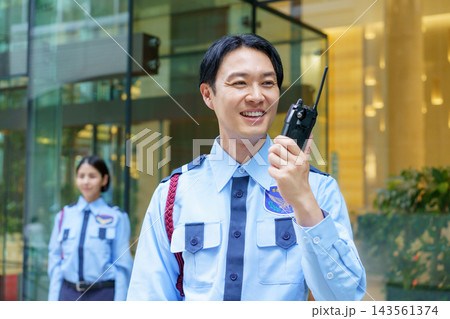 トランシーバーで会話する若い日本人男性警備員 143561374