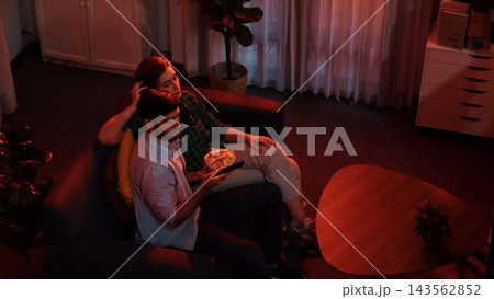 Happy father and mother watching TV together while eating snack. Convocation. 143562852