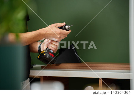 Man fitting drill bit into cordless drill before work 143564364