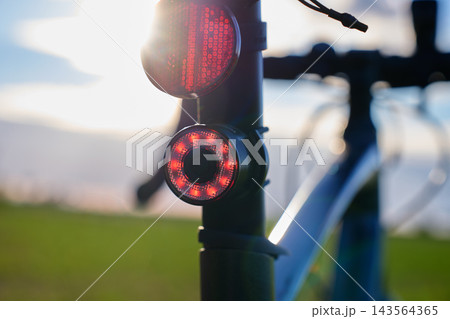 Close up of red bicycle lights glowing at sunset 143564365
