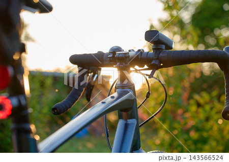 Gravel bike handlebars with front light at sunset Gravel bike handlebars with front light at sunset 143566524