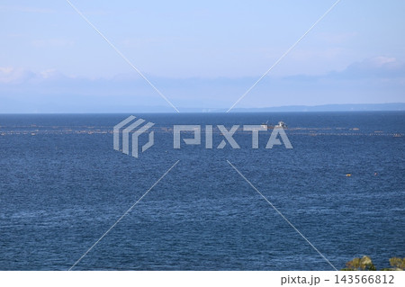 青い海面の海と船と霞む対岸のタンクや山と雲と青空の風景 143566812