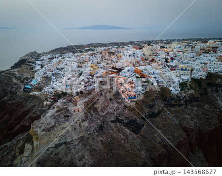 Aerial Drone View of Oia, Santorini. A breathtaking aerial view of the whitewashed village of Oia, Santorini, showcasing luxury resorts with infinity pools overlooking the Aegean Sea. A stunning blend 143568677