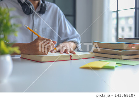 College Student Writing Research Notes During Online Learning and Academic Study Session at Home. College Student Writing Research Notes During Online Learning and Academic Study Session at Home. 143569107
