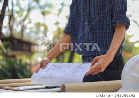 Civil engineer or site manager reviewing construction blueprints outdoors on a construction site Civil engineer or site manager reviewing construction blueprints outdoors on a construction site 143569142