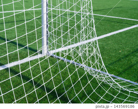Goal net and white marking lines on a green football stadium. Goal net and white marking lines on a green football stadium. 143569186