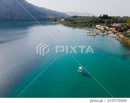 Aerial Panorama of Lake Kournas, Crete. Stunning aerial drone view of the natural Lake Kournas in Chania, Crete. The turquoise waters reflect the surrounding hills, while white pedal boats float peace 143570800
