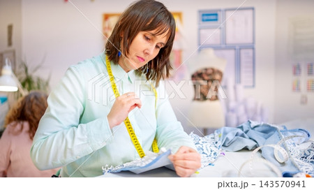 Woman working in sewing workshop preparing garment 143570941