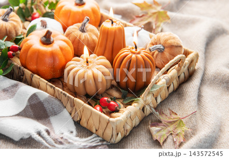 Autumn pumpkin candles burning in wicker tray on blanket Autumn pumpkin candles burning in wicker tray on blanket 143572545