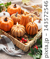 Autumn pumpkin candles burning in wicker tray on blanket 143572546