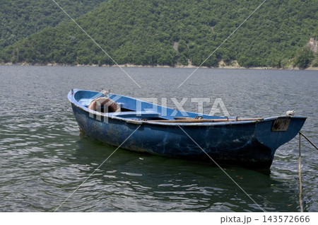 Weathered Blue Wooden Fishing Boat Moored on Calm Water 143572666