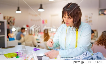 Seamstress hand stitching lace fabric in a sewing workshop 143573706