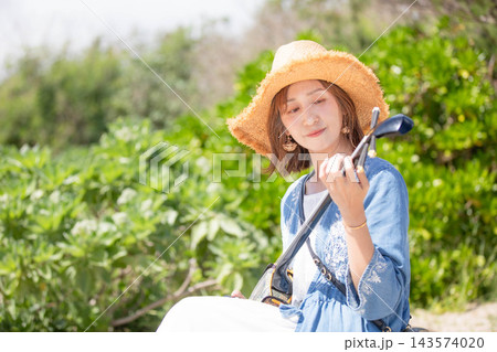 三線を弾く沖縄旅行の女性モデル 143574020