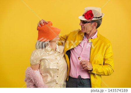 Senior couple enjoying vibrant healthy positive maturity against yellow Senior couple enjoying vibrant healthy positive maturity against yellow 143574189