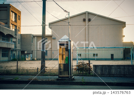 夕日に照らされる電話ボックスと学校の校庭 143576763