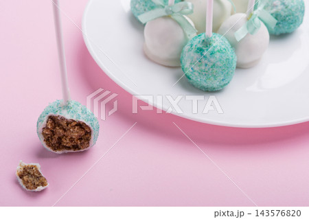 Bitten turquoise cake pop showing inner biscuit texture with cake pops on white plate Bitten turquoise cake pop showing inner biscuit texture with cake pops on white plate 143576820