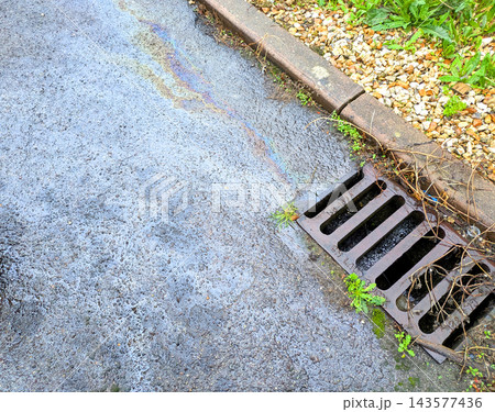 Oil spill from a petrol car on the road running down the drain pollution Oil spill from a petrol car on the road running down the drain pollution 143577436