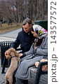 Couple relaxing on a bench during a walk in the park. A loving couple walks their dog outdoors during the cold season. 143577572