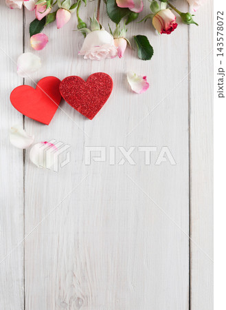 Valentine background with pink rose flowers and handmade wooden hearts, top view on white rustic wood, vertical orientation. Happy lovers day mockup, copy space 143578072
