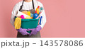 Bucket with cleaning supplies and tools in hands of unrecognizable man in apron standing on pink background, cropped image, panorana with free space 143578086