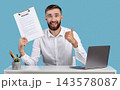 Happy Caucasian guy holding resume and showing thumb up gesture at his desk, blue studio background. HR manager finding perfect worker for business team. Successful employment and headhunting concept 143578087