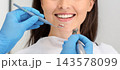 Beautiful smile concept. Smiling young woman attending dental clinic, hands of dentist with drilling tools, cropped 143578099