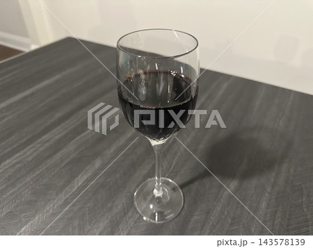 グレーのテーブルに置いた赤ワインのグラス1つ グレーのテーブルに置いた赤ワインのグラス1つ 143578139