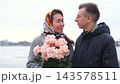 Mature couple kissing with a bouquet of roses by the river. Lasting love, intimacy and devotion. 143578511