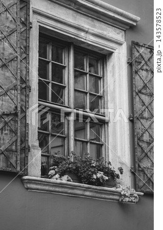 Wall with shutter windows and flower boxes, monochrome. Elegant architecture in Lviv, Ukraine. Facade decoration. Exterior design. House decoration with flower pots, black and white Wall with shutter windows and flower boxes, monochrome. Elegant architecture in Lviv, Ukraine. Facade decoration. Exterior design. House decoration with flower pots, black and white 143578523
