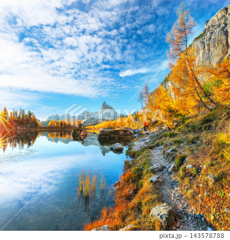 Amazing autumn view of  Lake Federa  at sunrise with majestic rocky mount and colorful trees glowing sunlight in Dolomites 143578788