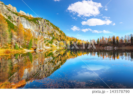 Amazing autumn view of Lake Federa at sunrise with majestic rocky mount and colorful trees glowing sunlight in Dolomites Amazing autumn view of Lake Federa at sunrise with majestic rocky mount and colorful trees glowing sunlight in Dolomites 143578790