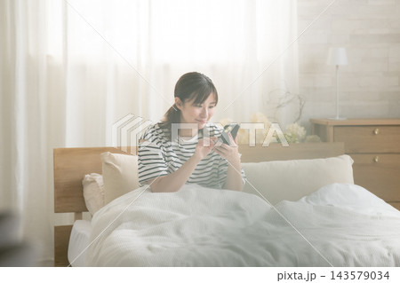 ベッドでスマホを見ている女性 ベッドでスマホを見ている女性 143579034