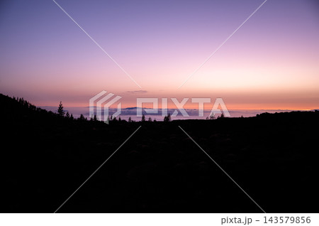 Violet afterglow above the cloud sea on Tenerife. Violet and peach afterglow spreads above the cloud sea seen from the high road in Teide National Park. Stillness and perspective for mindfulness  143579856