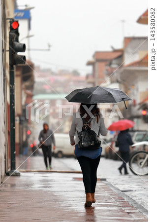 雨のエクアドル・クエンカ 傘をさして歩く女性の後ろ姿と旧市街の街並み 雨のエクアドル・クエンカ 傘をさして歩く女性の後ろ姿と旧市街の街並み 143580082