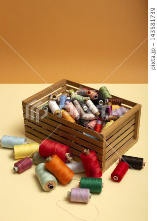 A box with multi colored coins of different threads on a colored background A box with multi colored coins of different threads on a colored background 143581739