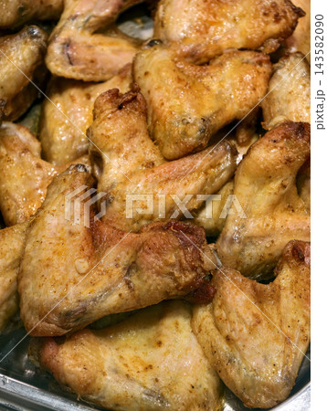 Fried chicken wings displayed in a supermarket deli, presenting cooked poultry arranged for sale in a grocery store prepared food section 143582090