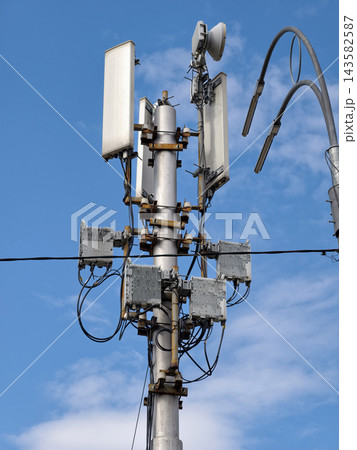 A communications antenna mounted on a low pole, with a streetlight beside it on the road 143582587