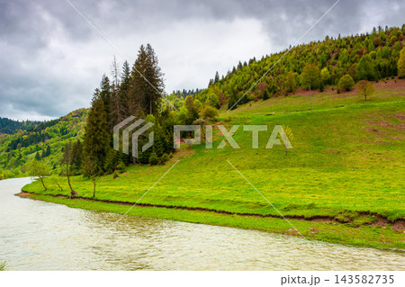 landscape with mountains, forest and a river in front. beautiful scenery in spring. cloudy sky landscape with mountains, forest and a river in front. beautiful scenery in spring. cloudy sky 143582735