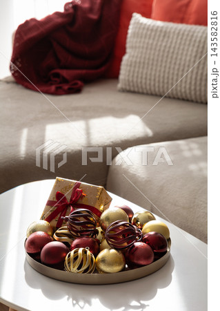 Cozy living room interior decorated for winter holidays with red and gold baubles 143582816