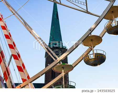 Amusement ride Ferris wheel near church under blue sky Amusement ride Ferris wheel near church under blue sky 143583025