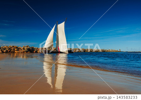 A sailboat with white sails in the beach of the Baltic sea 143583233