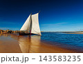 A sailboat with white sails in the beach of the Baltic sea 143583235