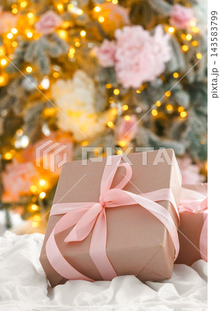 Soft pink Christmas gift box with ribbon on blurred holiday festive lights bokeh background Soft pink Christmas gift box with ribbon on blurred holiday festive lights bokeh background 143583799